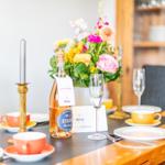 Set dining table with flowers, glasses, and a bottle of sparkling wine.