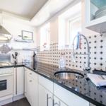 Kitchen with white cabinets, black countertop, and patterned tile backsplash
