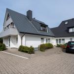 Wohnhaus mit Balkon, gepflasterter Hof und parkendem Auto.