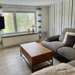 Wohnzimmer mit Sofa, Couchtisch und Fenster. Wand mit Streifen. Fernseher an der Wand.
