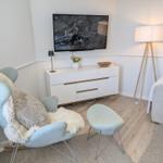 Wohnzimmer mit Fernseher, Sessel und Stehlampe.
