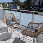 Terrasse mit zwei Stühlen und Tisch. Blick auf Wohngebiet mit Häusern und Bäumen.