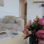 Ein Wohnzimmer mit einem Sofa, einem Tisch und einer Blumenvase.