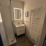 Badezimmer mit Dusche, Waschbecken und Heizkörper