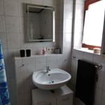 Badezimmer mit Waschbecken, Spiegel und Fenster. Duschvorhang und Handtuch sind vorhanden.