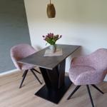 Essbereich mit Tisch, zwei Stühlen und Blumenarrangement.