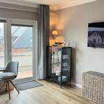 Wohnbereich mit TV, Glasvitrine und Balkonansicht
