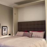 Schlafzimmer mit Bett, Kopfteil und Wandbeleuchtung
