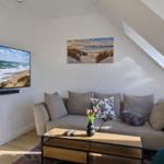 Wohnzimmer mit Sofa, Fernseher und Wandbild.