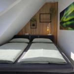 Schlafzimmer mit Doppelbett, Holzwand und Wandbild