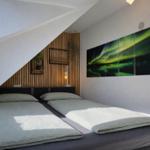 Schlafzimmer mit Doppelbett, Holzwand und Nordlicht-Bild an der Wand.