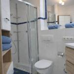 Badezimmer mit Dusche, Toilette und Waschbecken mit blauen Handtüchern.