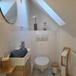 Badezimmer mit Toilette, Waschbecken und Spiegel unter Dachschrägen.