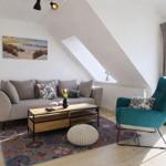 Wohnzimmer mit Sofa, Sessel und Fenster. Decke geneigt. Teppich und Couchtisch.