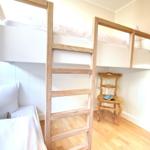 Upper and lower bunk beds with wooden ladder and chair.