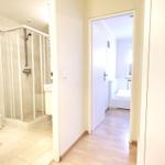 Bathroom with shower and bedroom with bed visible.