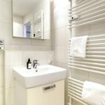 Bathroom with sink, mirror, and heated towel rack with towels.