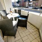 Balcony with table and four chairs, bottle and glasses on it.