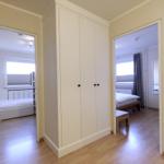 Two bedrooms with beds and windows. Between them stands a white wardrobe.