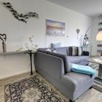 Ein Wohnzimmer mit grauem Sofa, Teppich und Wanddekoration.