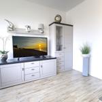 Wohnzimmer mit Fernseher, Schrank und Pflanzen auf Holzboden.