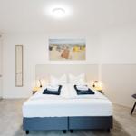 Schlafzimmer mit Doppelbett, Kleiderschrank und Wandbild.