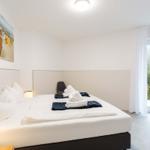Schlafzimmer mit Doppelbett, Balkon und Strandbild an der Wand.