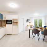 Küche mit Essbereich und Wohnzimmer mit Balkon.