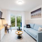 Wohnzimmer mit Sofa, TV und Balkonansicht