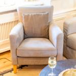 Ein bequemer Sessel mit Kissen steht neben einem Sofa.
