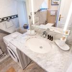 Badezimmer mit Waschmaschine, Waschtisch und Spiegel