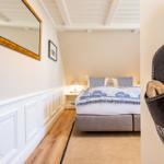 Schlafzimmer mit Bett, Spiegel und Holzboden