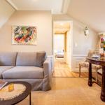 Wohn- und Essbereich mit Sofa, Tisch und Blick in Schlafzimmer.