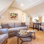Wohnzimmer mit Sofa, Sessel und Tisch unter schrägen Dachschrägen.