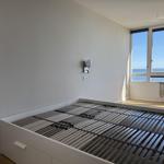 Bedroom with bed frame and sea view through large windows.
