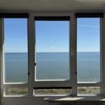 Large window with sea view. View of calm water under blue sky.