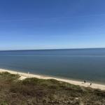 Beach with sand and sea under blue sky with few people.