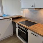 Kitchen with cooktop and oven, wooden worktop, window with sea view.