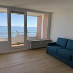 Living room with blue sofa and sea view through large windows.