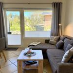 Wohnzimmer mit Sofa, Couchtisch und Fenster zum Garten