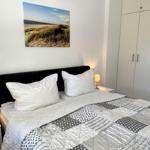 Schlafzimmer mit Bett, Nachttischen und Kleiderschrank. Wandbild zeigt Strand.