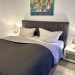 Schlafzimmer mit Bett, zwei Nachttischen und Wandbild.