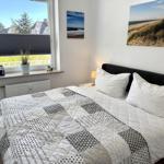 Schlafzimmer mit Bett, Fenster und Wandbildern.