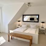 Schlafzimmer mit Doppelbett, zwei Nachttischen und Spiegel an der Wand.