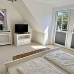 Schlafzimmer mit Dachschräge, TV und Balkontür.