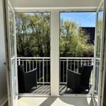 Terrasse mit zwei schwarzen Stühlen und Blick auf Bäume.