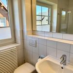 Badezimmer mit Waschbecken, Spiegel und Dusche. Fenster mit Jalousie.