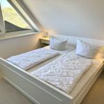 Zimmer mit Doppelbett, zwei Nachttischen und Dachfenster mit Blick.