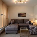 Ein Wohnzimmer mit grauem Sofa, Glas-Tisch und Beistelltisch.