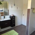Badezimmer mit Waschbecken, Spiegel und Dusche. Grün Teppich und Handtuch.